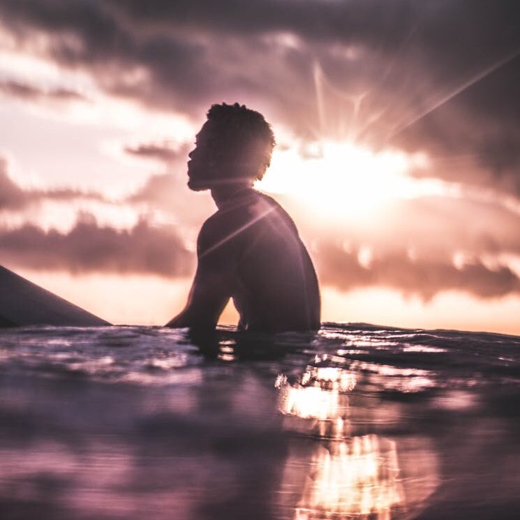 Unrecognizable black man relaxing in sea water at sundown